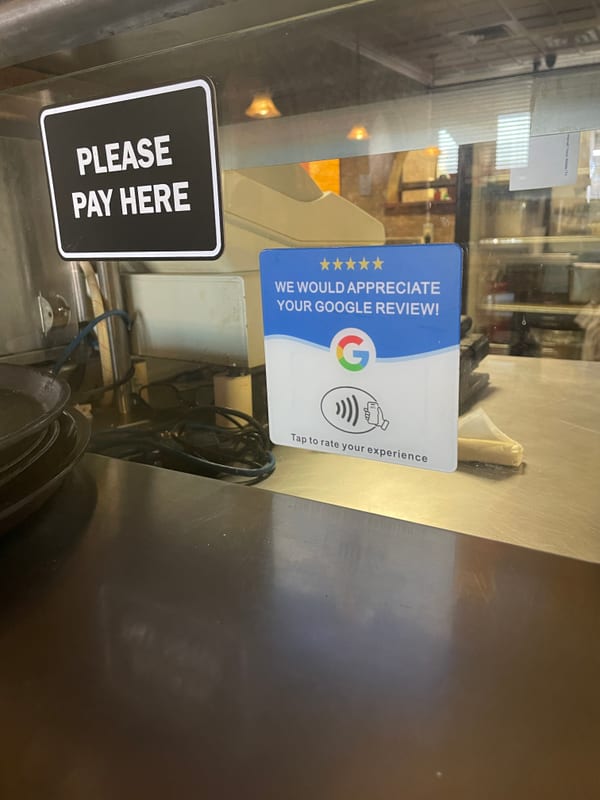 An NFC review card next to a register at a business counter.